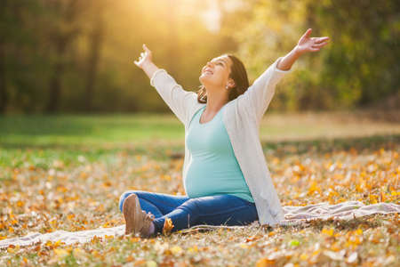 Happy pregnant woman relaxing in park.の写真素材