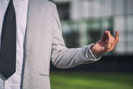 Businessman is meditating outside the company building.