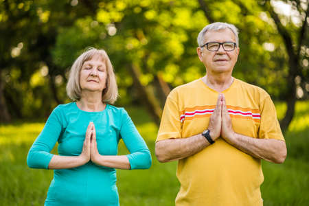 Senior couple is meditating in park.の写真素材