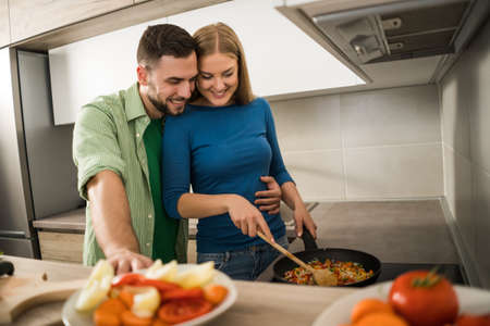 Young couple is preparing meal in their kitchen.の写真素材