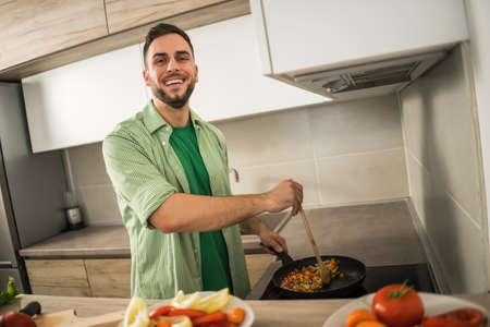 Young man is preparing meal in his kitchen.