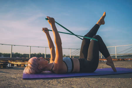 Woman exercising pilates with elastic band on sunny day.の写真素材