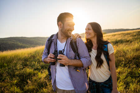 Happy couple is hiking in mountain. They are watching nature with binoculars.の写真素材