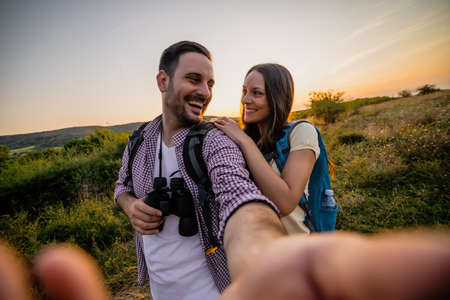 Happy couple is hiking. They are having fun with wide ange lens on camera.の写真素材
