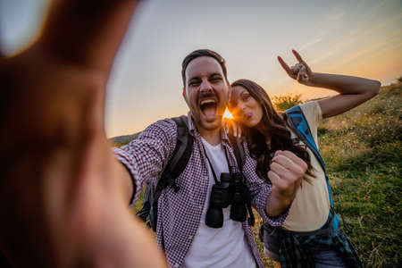 Happy couple is hiking. They are having fun with wide ange lens on camera.の写真素材