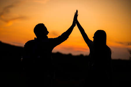 Happy couple is hiking in mountain in sunset.