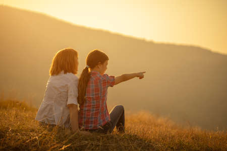 Happy grandmother and granddaughter enjoying nature and sunset.の写真素材