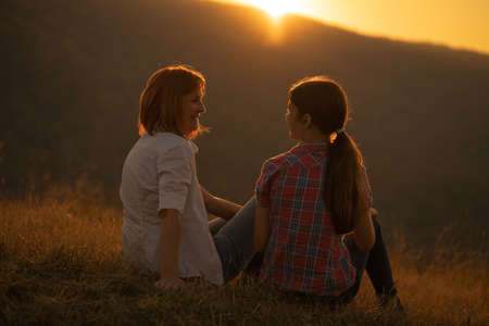 Happy grandmother and granddaughter enjoying nature and sunset.の写真素材