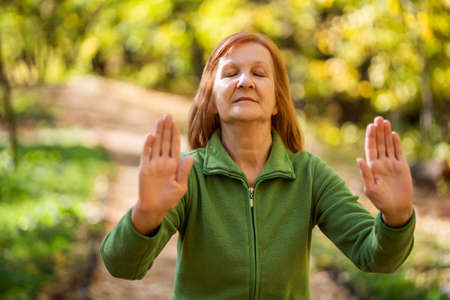 Senior woman is practicing Tai Chi exercise in park.