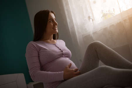 Happy pregnant woman relaxing at home.