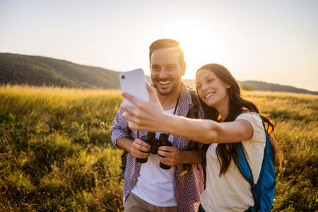 Happy couple is hiking in mountain. They are taking selfie.の写真素材