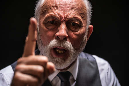 Portrait of angry senior man who threatens. Black background.の写真素材