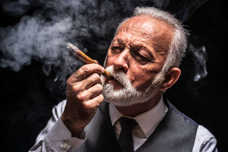 Portrait of serious senior man who is smoking cigar.の写真素材