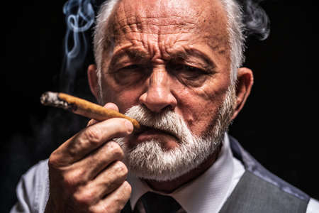 Portrait of serious senior man who is smoking cigar.の写真素材