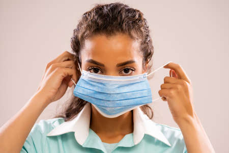 Portrait of young nurse putting medical mask.の写真素材