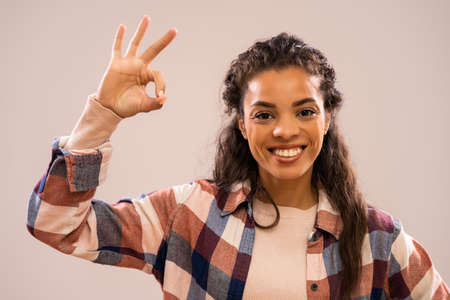 Studio shot portrait of beautiful happy african-american ethnicity woman in casual clothing showing ok hand sign.の写真素材