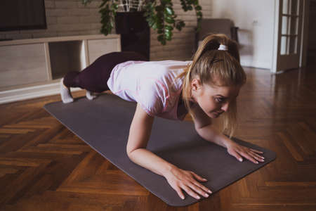 Young woman practicing pilates and yoga exercises at home. She is doing push-ups.の写真素材