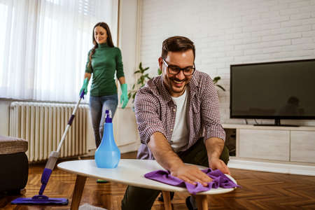 Young happy couple is cleaning their apartment.