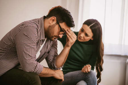 Man is sad and depressed, his wife is consoling him.の写真素材