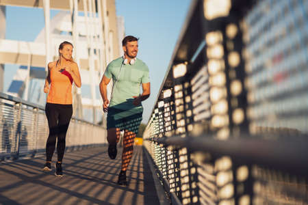 Young couple is jogging on bridge in the city.