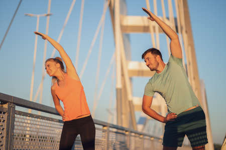 Young couple is exercising outdoor on bridge in the city.の写真素材
