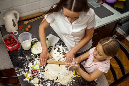 Mother and daughter are making cookies in kitchen.