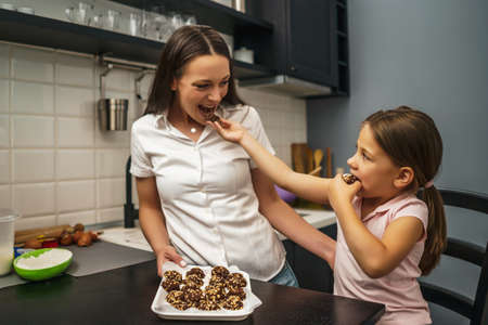 Mother and daughter have made cookies in their kitchen. They are tasting it.の写真素材