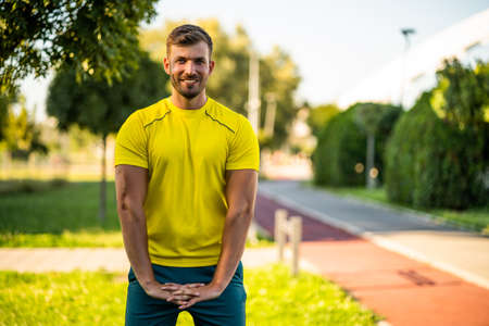 Young man is exercising outdoor. He is stretching his body and warming up for jogging.の写真素材