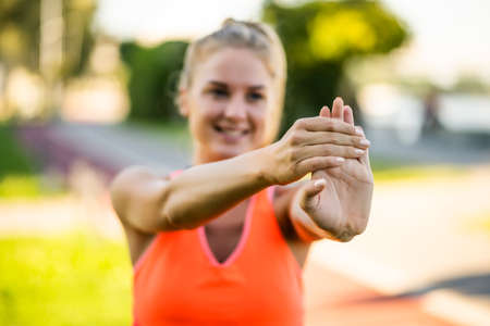 Young woman is exercising outdoor. She is stretching her body and warming up for jogging.の写真素材