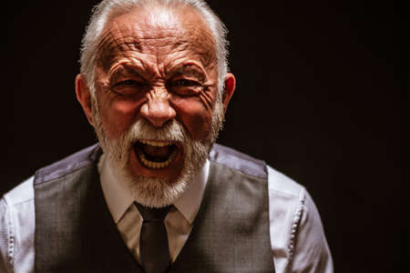 Portrait of furious senior man who is screaming. Black background.の写真素材