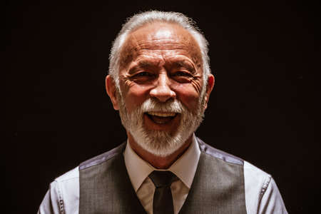 Portrait of cheerful senior man on black background.の写真素材