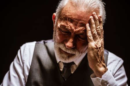 Portrait of depressed senior man on black background.の写真素材