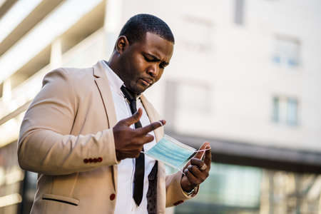 Portrait of african-american businessman who hates wearing protective mask. Covid-19 virus pandemic concept.の写真素材