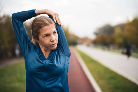 Beautiful adult woman is exercising outdoor on cloudy day in autumn.の写真素材