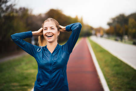 Beautiful adult woman is getting ready for outdoor exercising on cloudy day in autumn.の写真素材