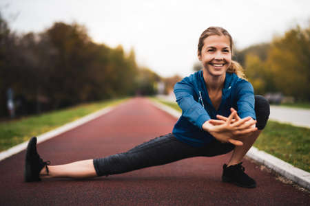 Beautiful adult woman is exercising outdoor on cloudy day in autumn.の写真素材