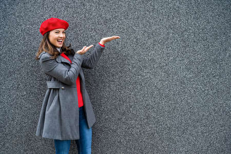 Adult woman in modern casual clothing standing in front of gray background. She is cheerful and looking at camera. Copy space for your advert.の写真素材
