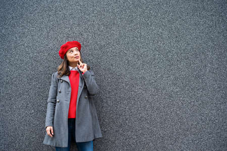 Adult woman in modern casual clothing standing in front of gray background. She is cheerful and looking at camera. Copy space for your advert.の写真素材