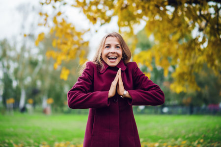 Portrait of happy blonde woman in park in autumn. She is enjoying nature.の写真素材