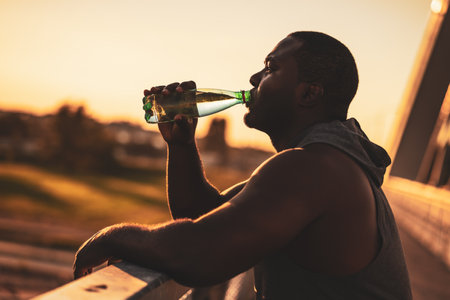 Portrait of young african-american man in sports clothing who is drinking water after exercise. He is exercising to reduce his body weight.の写真素材