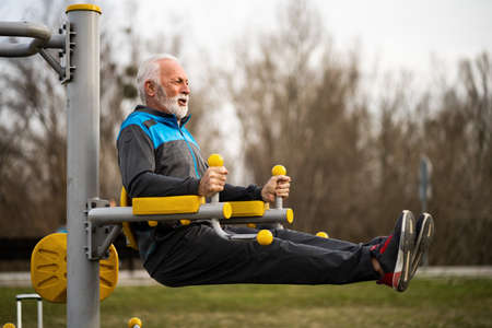 Active senior man is exercising on outdoor gym. Healthy retirement lifestyle.の写真素材