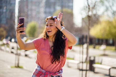 Happy young woman is enjoying sunny day outdoor in city.