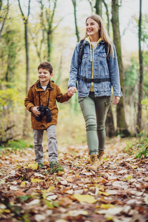 Happy mother and son are hiking in forest in autumn.の写真素材
