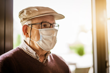 Indoor close up portrait of senior man who is wearing face protection mask. Covid 19 prevention concept.の写真素材