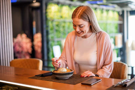 Young happy woman is eating dessert at restaurant.の写真素材