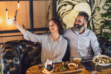 Happy couple is sitting at restaurant. They are having dinner with wine and spending nice time...