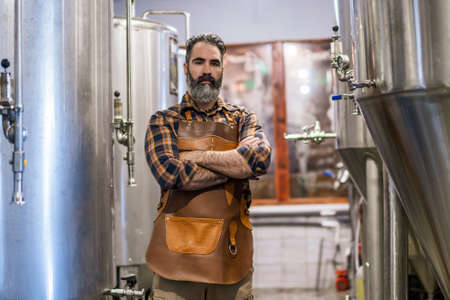 Man is working at craft beer factory. He is operating machinery in brewery. Small family business,...