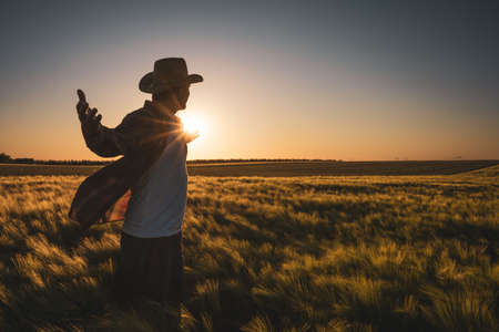 Adult man is cultivating barley on his land. He is satisfied because of good progress of crops.の素材 [FY310188369126]