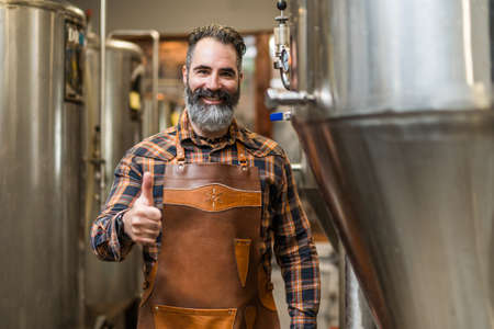 Portrait of man who is working at craft beer factory. Small family business, production of craft...
