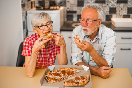 Senior couple eating pizza at home.の写真素材